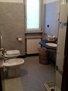 een badkamer met 2 toiletten, een wastafel en een raam bij Morbegno house in Morbegno