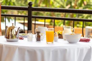 una mesa con un mantel blanco con un vaso de zumo de naranja en Rayan Apartments & Safaris, en Arusha