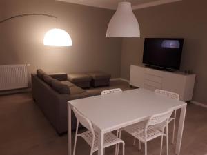 Wielicka Apartment 2 في كراكوف: غرفة معيشة مع طاولة وكراسي بيضاء