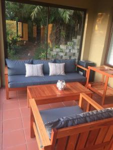 a patio with a blue couch and wooden tables at 20A Castleton in Plettenberg Bay