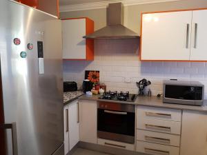 a kitchen with white cabinets and a stove and a microwave at 20A Castleton in Plettenberg Bay +2 photos