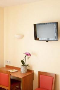 a room with a table and a tv on the wall at Le Robinson in Saint-Jean-de-Monts