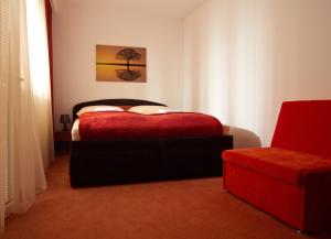 1 dormitorio con 1 cama roja y 1 silla en Penzión Donet, en Bratislava