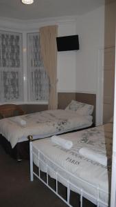 two beds in a room with a tv on the wall at Hornby House Hotel in Blackpool