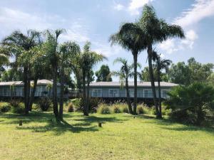 a building with palm trees in front of a field at La Posada Multiespacios in Dique Luján