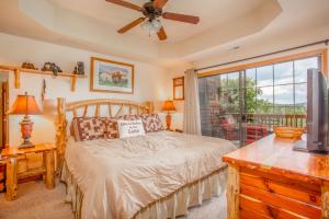 a bedroom with a bed with a ceiling fan and a window at The Village At Indian Point Resort in Branson