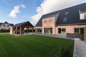 a large lawn in front of a brick building at Duins Genot 5 star Holiday Homes 30p & 40p - Indoorpool & Wellness in Jabbeke