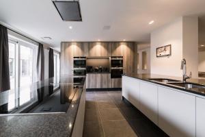 a kitchen with white cabinets and black counter tops at Duins Genot 5 star Holiday Homes 30p & 40p - Indoorpool & Wellness in Jabbeke