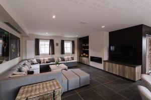 a living room with a large couch and a tv at Duins Genot 5 star Holiday Homes 30p & 40p - Indoorpool & Wellness in Jabbeke