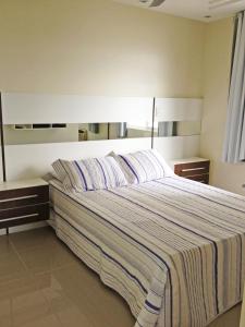 a bedroom with a large bed with a striped blanket at ILHAS CANARIAS APTO 101 in Florianópolis