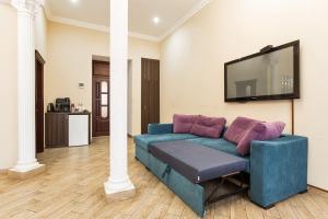 a living room with a blue couch and a flat screen tv at Hotel Baron in Odesa