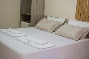 Una cama blanca con dos servilletas encima. en Hotel Boulevard, en Araripina