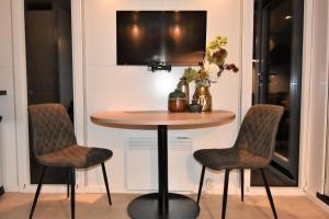 een tafel met twee stoelen en een televisie aan de muur bij Cozy floating boatlodge "Maastricht". in Maastricht