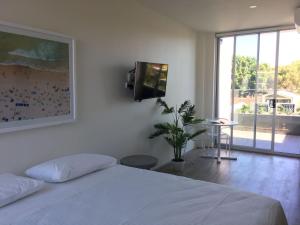 a bedroom with a bed and a tv on a wall at Bondi Beach Studio Penthouse Suite + Balcony in Sydney