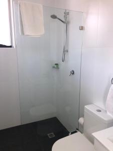 a white bathroom with a shower and a toilet at Bondi Beach Studio Penthouse Suite + Balcony in Sydney +2 photos