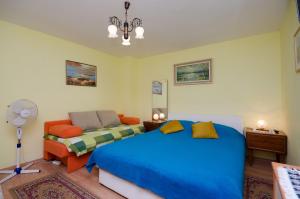 a bedroom with a bed and a chair and a fan at Apartments Jasminka in Selce