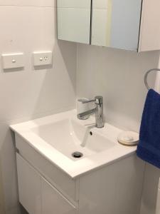 a white bathroom with a sink and a blue towel at Bondi Beach Studio King Suite 1 in Sydney