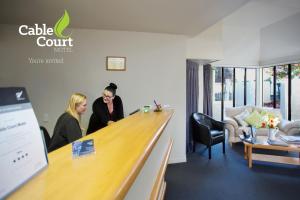 two people standing at a bar in a waiting room at Cable Court Motel in Dunedin