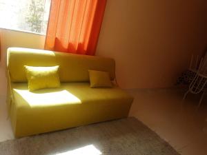- un canapé vert avec deux oreillers jaunes dans l'établissement Flat - Coroa Vermelha, à Santa Cruz Cabrália