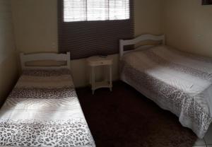 two beds in a small room with a window at Kit net de Temporada em Gramado in Gramado