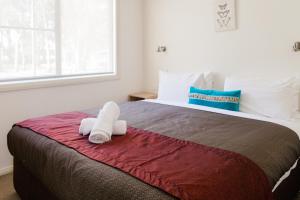 1 dormitorio con 1 cama con 2 toallas en McLean Beach Holiday Park, en Deniliquin