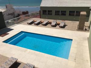 a swimming pool on top of a building with lounge chairs at Hotel Riviera in Las Grutas