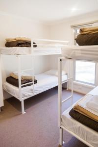 um quarto com beliches brancos num quarto em McLean Beach Holiday Park em Deniliquin