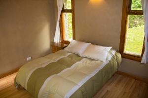 1 cama grande en un dormitorio con 2 ventanas en Mutisia Puerto Manzano en Villa La Angostura