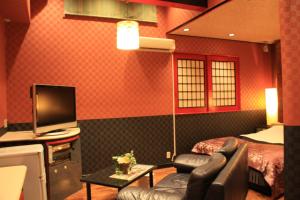 Habitación de hotel con cama, TV y sofá en Restay Moon Kochi (Adult Only), en Mimase