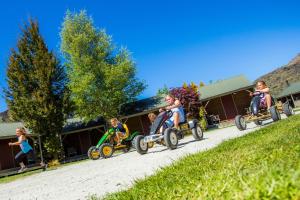 a group of children riding on tricycles down a road at Apartments at Queenstown TOP 10 Holiday Park in Queenstown