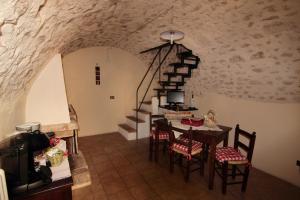a dining room with a table and a staircase in a stone building at Residenza La Torre in Santo Stefano di Sessanio
