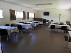 a dining room with tables and chairs and a tv at Mawley Holiday Park in Masterton