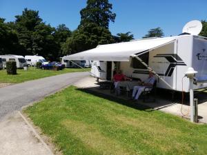 Due persone sedute a un tavolo di fronte a una roulotte di Mawley Holiday Park a Masterton