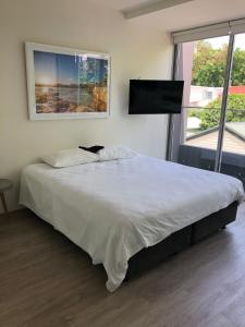a bedroom with a large bed and a flat screen tv at Bondi Beach Studio King Suite + Balcony in Sydney