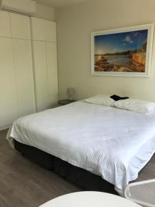 sypialnia z dużym białym łóżkiem z obrazem na ścianie w obiekcie Bondi Beach Studio King Suite + Balcony w mieście Sydney
