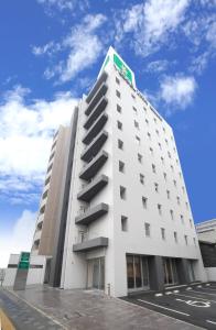 a white building with a green sign on top of it at Vessel Inn Hiroshima Ekimae in Hiroshima
