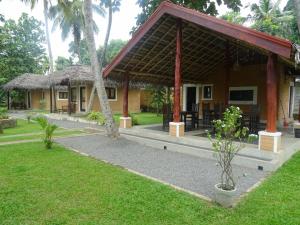 a resort with a building with a grass roof at airport eco cottage in Katunayaka