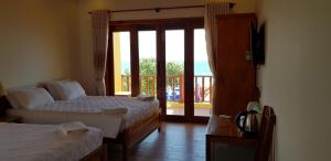 a bedroom with two beds and a door to a balcony at Free Beach Resort in Phú Quốc