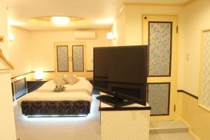 a bedroom with a bed and a flat screen tv at Pal Annex Munakata (Love Hotel) in Munakata