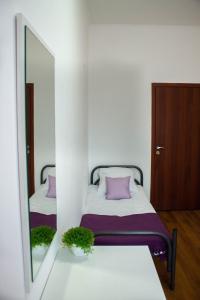 1 dormitorio con 2 camas con almohadas moradas y espejo en Simple Seasons Rooms - Самозаселение, en San Petersburgo