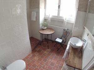 une salle de bain avec une table et un lavabo et des toilettes dans l'établissement Maison d'hôtes Fleurs de Vignes, à Montagny-lès-Beaune