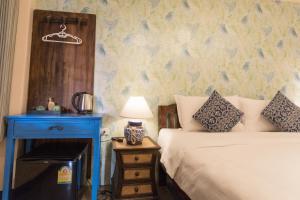 清邁的住宿－薩姆旺精品酒店，一间卧室配有一张床和一个带灯的床头柜