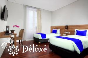 Cette chambre comprend 2 lits et un bureau. dans l'établissement Hotel Namira Syariah Pekalongan, à Pekalongan