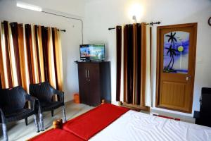 a bedroom with a bed and two chairs and a television at Mountain Breeze Villa and Homestay in Idukki