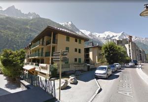 un bâtiment avec des voitures garées dans un parking avec des montagnes dans l'établissement La Chabane, à Chamonix-Mont-Blanc
