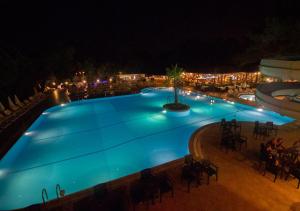 una gran piscina por la noche con gente sentada alrededor en Hotel Greenland - All Inclusive en Oludeniz
