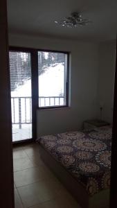 um quarto com uma cama e uma grande janela em Grand Monastery - Azure Apartment em Pamporovo