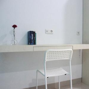 einen weißen Schreibtisch mit einem Stuhl und eine Vase mit einer Blume in der Unterkunft Rumah99 in Jakarta