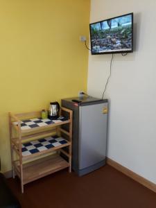 a small refrigerator in a room with a tv on the wall at Elephant & Castle in Ko Chang
