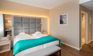 a bedroom with a large bed with a green blanket at Hollywood Media Hotel am Kurfürstendamm in Berlin